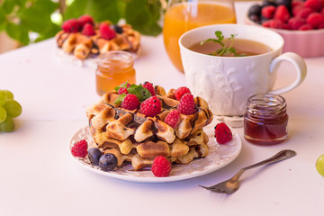 Belgium waffles with raspberries, chocolate and syrup on a plate.