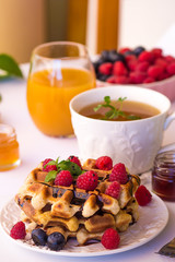 Belgium waffles with raspberries, chocolate and syrup on a plate.
