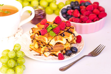 Belgium waffles with raspberries, chocolate and syrup on a plate.