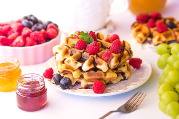 Belgium waffles with raspberries, chocolate and syrup on a plate.