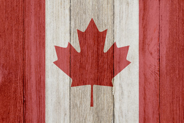 A rustic old Canadian flag on weathered wood