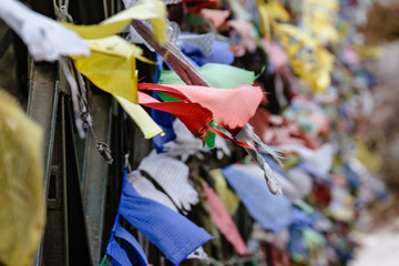 Tear colorful Tibetan prayer flags waving and swaddled with bridge over frozen river at Thangu and Chopta valley in winter in Lachen. North Sikkim, India.