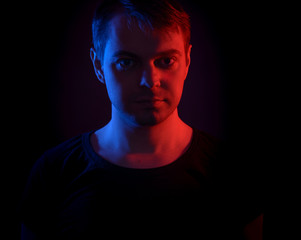 Portrait of a man with colored light and dark background.