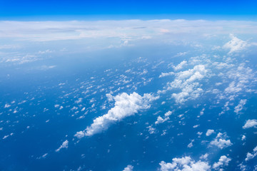 Naklejka premium Flying into blue sky and sea of fantasy row clouds and Wing of airplane with skyline top view as look from window airplane, during flight space for text message, frame or traveling idea concept