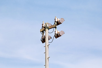 Stadium floodlight tower with reflectors with blue sky. Lighting pole tower at the sports stadium and ground. Big lamp and light stadium poles or sports lighting. Flood light pole in the spotlight.