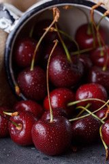 Red cherry in an enameled mug on a background of textile sackcloth.