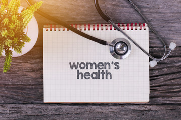 Women's Health word on notebook,stethoscope and green plan.