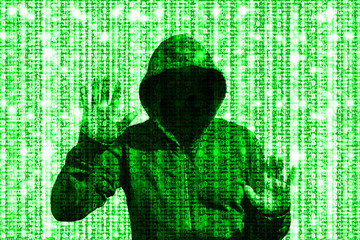 Shining green hacker behind computer code matrix