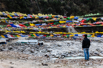 Tourist see Tibetan prayer flags waving and swaddled with trees an mountain in sideway over frozen river at Thangu and Chopta valley in winter in Lachen. North Sikkim, India.