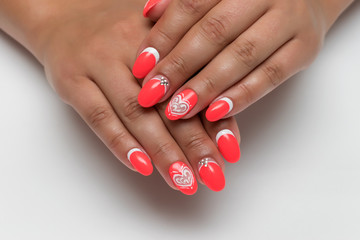 Year-old red-white manicure with a white heart and crystals on long oval nails on tanned hands  