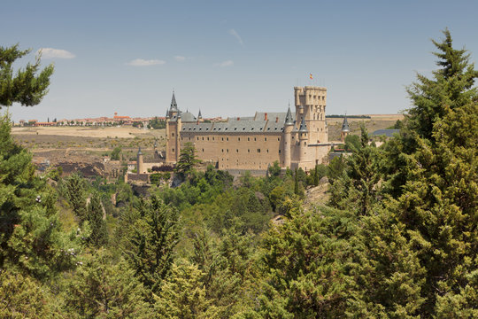 Alcazar of Segovia seen through the trees forest 