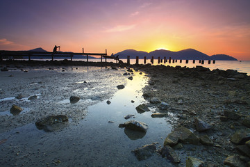 A silhouette of photographer taking a picture of abandoned fisherman during beautiful sunset