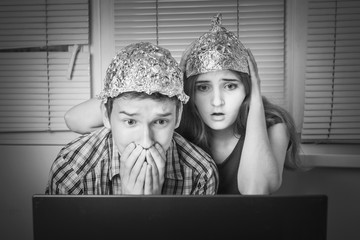 Teens boy and girl  in hats made of aluminum foil, protect the brain from unnecessary radiation