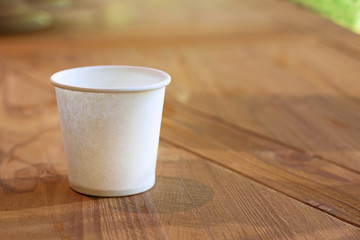 paper cup on wooden table with sunshine and natural background