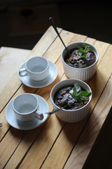 Healthy breakfast of oat pudding in white keraimic mold. Decorated with sprig of mint and powdered sugar. Two empty cups