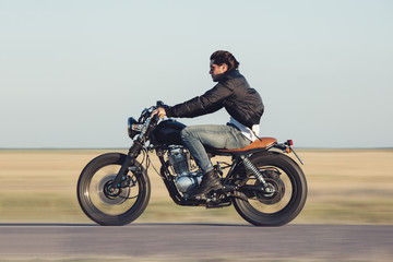 Young man riding a vintage motorcycle. Camera panning for motion blur.