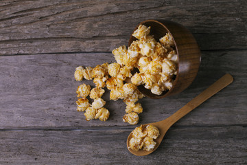 Caramel popcorn in the bowl wooden background.