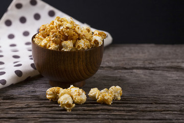 Caramel popcorn in the bowl wooden background.