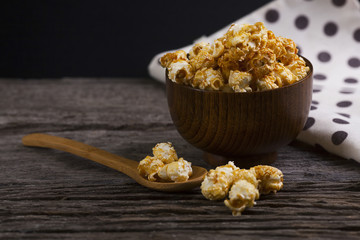 Caramel popcorn in the bowl wooden background.