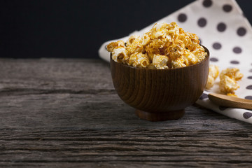 Caramel popcorn in the bowl wooden background.