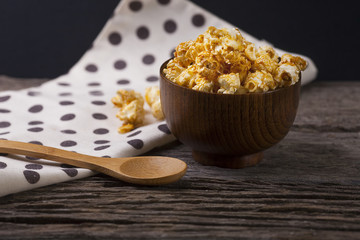 Caramel popcorn in the bowl wooden background.