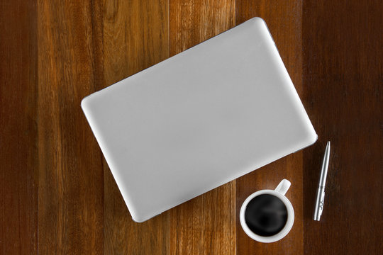 Top view of  Cup of coffee ,pen and a laptop on wooden table background.