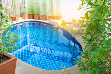 select tive focus of The Lovely pool with grab bars ladder pool in the garden and sunshine background.