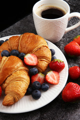 Delicious breakfast with fresh croissants and ripe berries on old marble background