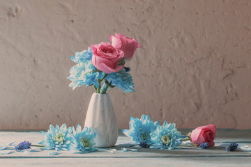 blue and pink flowers in vase on white grunge background