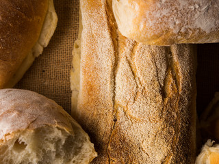 Freshly baked bread loaves on burlap dark wooden background. Texture closeup italian bakery products