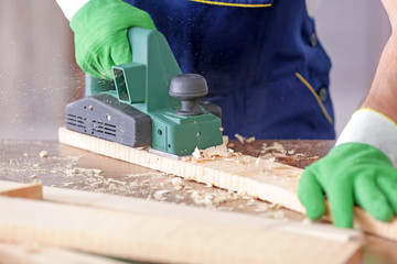 Carpenter working with electric plane, closeup