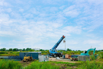 Selective focus of construction and excavator are filling the dump trucks with soil in the construction site with blue sky floor.