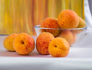 Bright yellow and orange auricos on a white tablecloth in a glass vase
