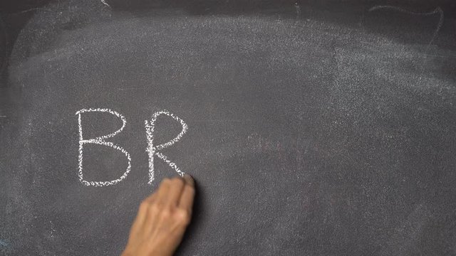 Woman's hand writing "BRAIN" with white chalk on blackboard