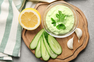 Delicious yogurt sauce in bowl with ingredients on kitchen table
