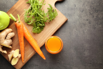 Glass of juice and fresh carrot on cutting board