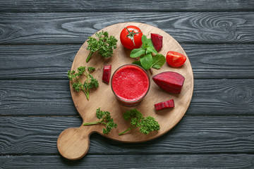 Red smoothie, fresh vegetables and herbs on wooden board