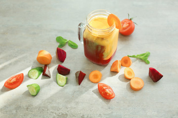 Mason jar with fresh smoothie and sliced vegetables on table