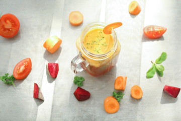 Mason jar with fresh smoothie and sliced vegetables on table