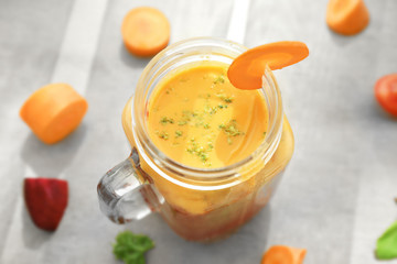 Mason jar with fresh smoothie and sliced vegetables on table