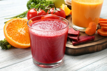 Fresh smoothies, vegetables and orange slice on table