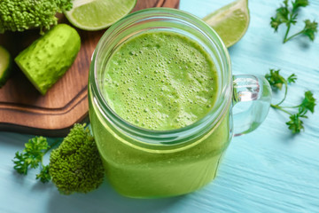 Mason jar with fresh green smoothie on wooden table