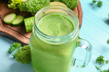 Mason jar with fresh green smoothie on table, closeup