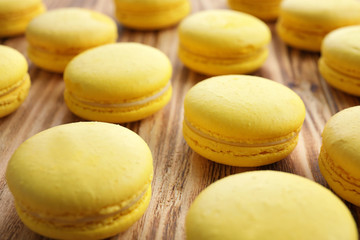 Tasty lemon macarons on wooden table, closeup
