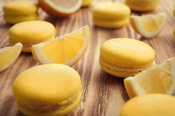 Tasty fresh macarons and lemon slices on wooden table, closeup