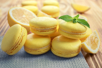 Tasty lemon macarons on wooden table, closeup