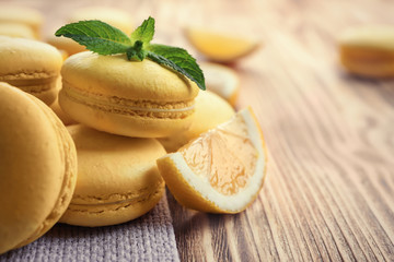 Tasty lemon macarons on wooden table, closeup