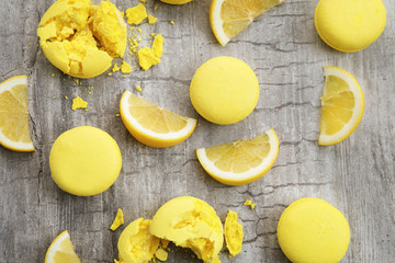 Tasty fresh macarons and lemon slices on wooden table