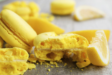 Fresh macarons and lemon slice on wooden table, closeup