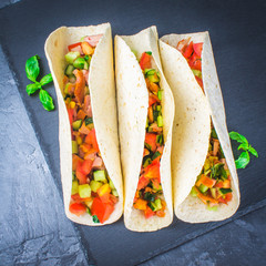 Traditional Mexican tacos with meat and vegetables on wooden background